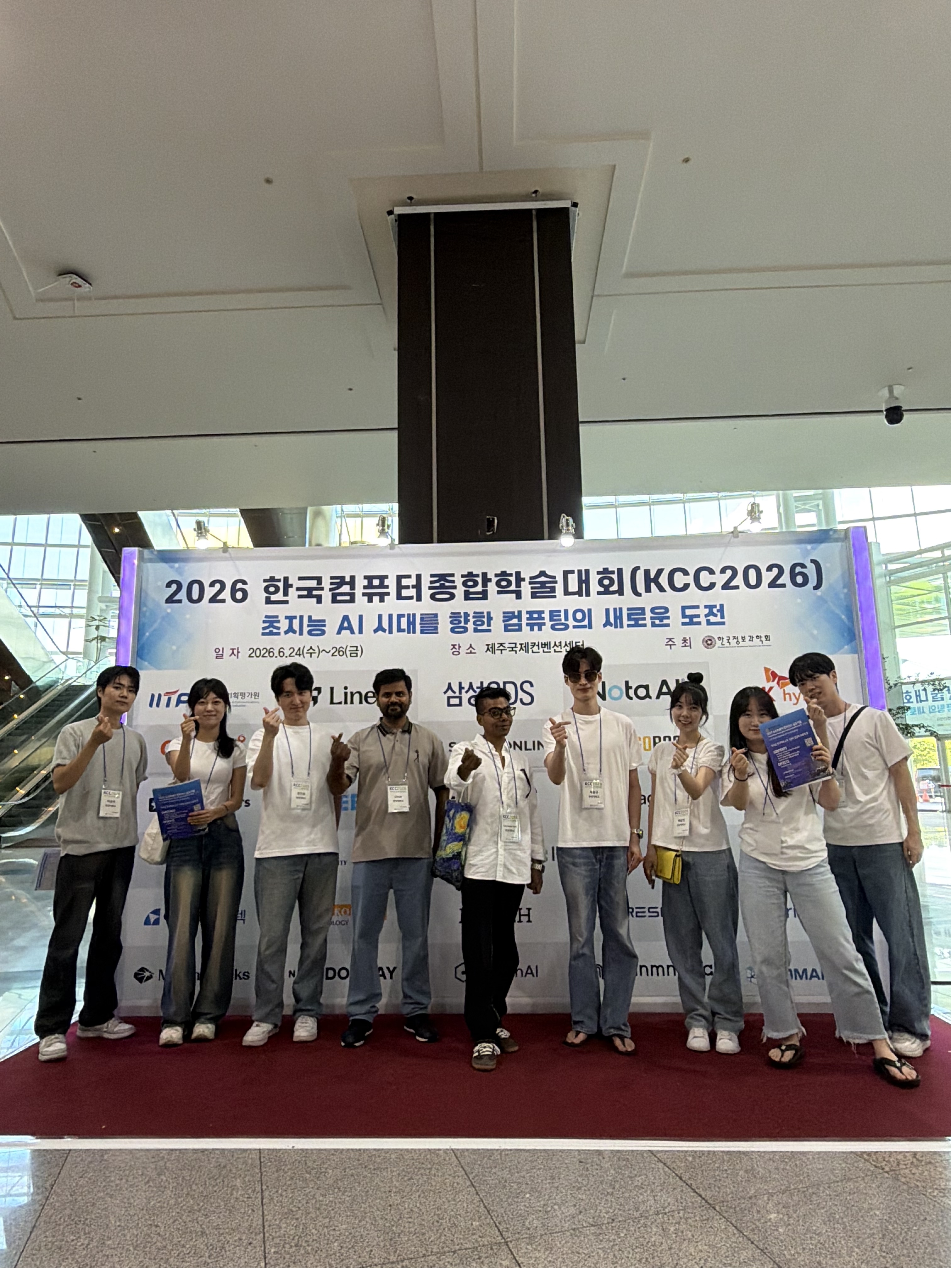 KCC 2026 학회 현수막 앞 연구실 단체 사진